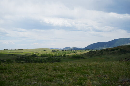 Rolling Green Hills and Mountain Landscape Under a Cloudy Sky Near Boulder, Colorado