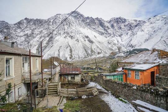 Traditional houses of Stepantsminda town with snowy Caucasus Mountains, including Mount Kazbek, in Georgia