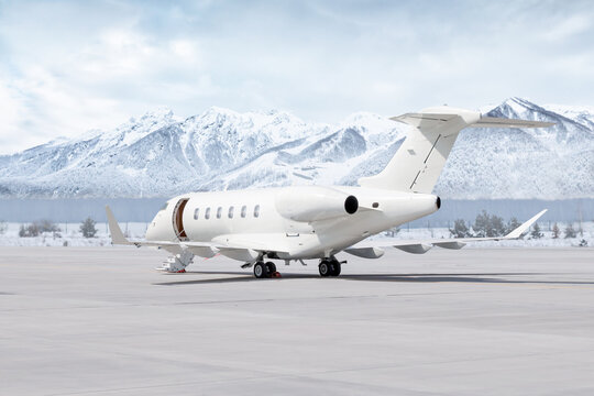 Modern white corporate airplane with an opened gangway door at the winter airport on the background of high snow capped mountains