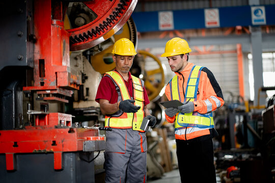 professional engineer,worker,technician use clipboard discuss work, walk in steel metal manufacture factory plant industry. Black African American man and woman wear hard hat check quality machine.