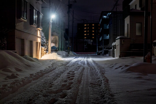 轍が残る夜の積雪した住宅街の道路、北海道札幌市