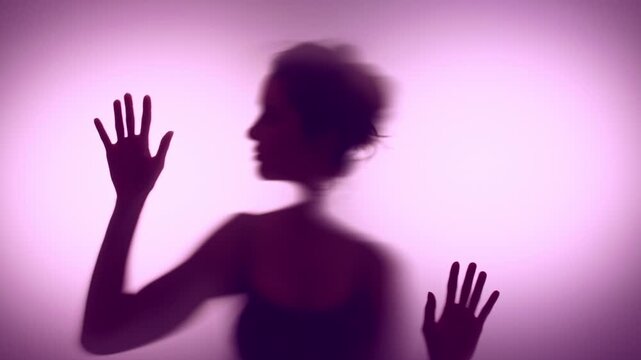 Anonymous young woman touching pink matte glass in hope to get out of her loneliness and mental state. 