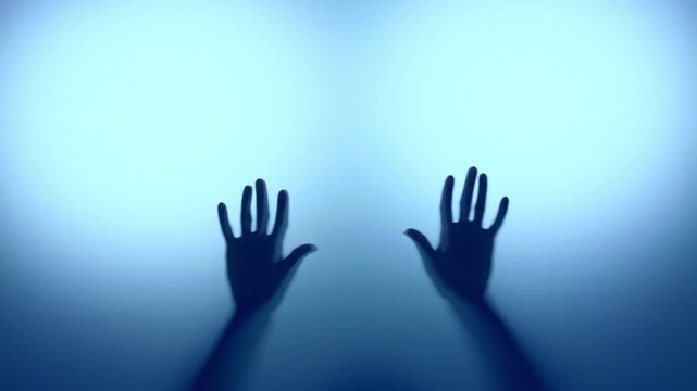 Anonymous woman touching frost glass in blue light with two hands. 