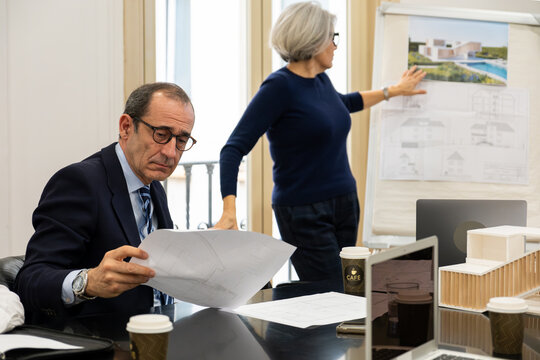 Professionals reviewing blueprints and architectural model during a business meeting
