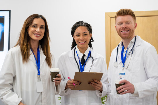 Diverse medical team standing together, smiling at the camera, wearing white lab coats and stethoscopes