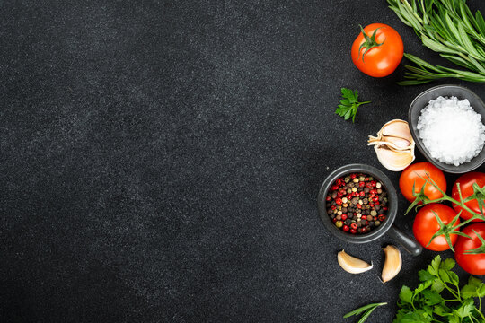 Food background on black. Fresh herbs, spices and vegetables on black table.