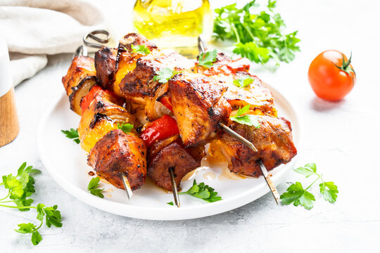 Grilled meat on skewers on light stone table.