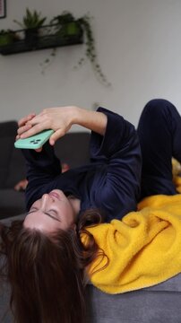 Vertical screen Phone in hand before sunrise becomes an automatic reflex as a young woman spends her first waking moments feeding endless social media habits every day