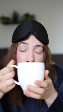 Vertical screen Before fully waking up a sleepy young woman instinctively reaches for coffee showing how morning caffeine becomes an automatic daily habit