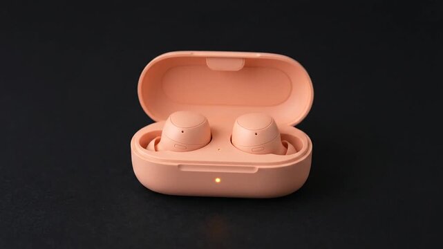 Pink wireless earbuds and charging case on a dark background.