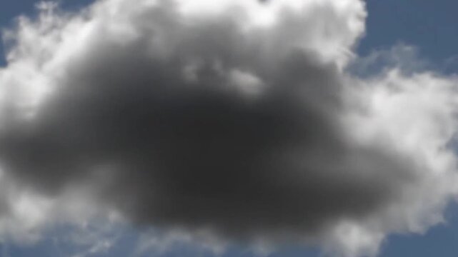 A single dark storm cloud floats against a clear blue sky