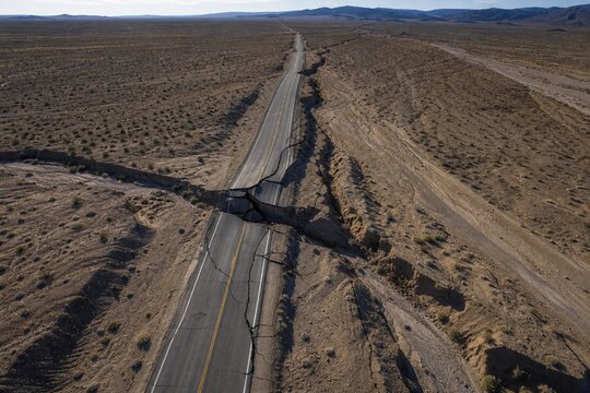 Aerial view of a cracked desert highway with severe lateral dislocation.