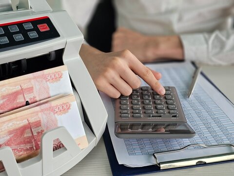 Cash handling and calculation at a desk with currencies and documents