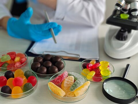 Scientist examines candies in laboratory setting with microscope