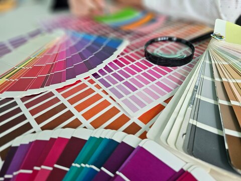 Color swatches are arranged on a table with a magnifying glass in a design studio where a project