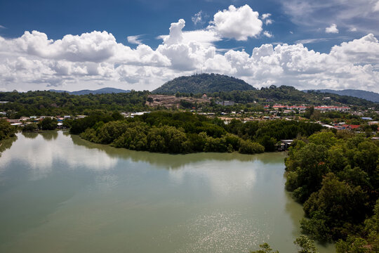 Tropical river flowing through dense green jungle and mangrove forest under blue sky