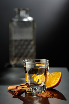 Mexican gold tequila with an orange slice and cinnamon on a black table.
