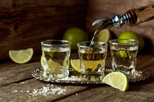 Tequila with salt and lime slices on a silver tray.