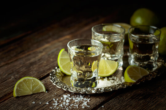 Tequila with salt and lime slices on a silver tray.