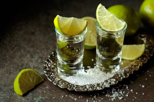 Tequila with salt and lime slices on a silver tray.