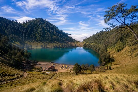 Aerial view of Ranu Kumbolo crater lake with camping tents on grassy shore, Mount Semeru National Park, East Java, Indonesia