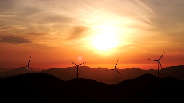 Wind Turbines Silhouetted Against a Golden Sunrise Over Mountain Ridges, Real Time Footage of Renewable Energy at Dawn