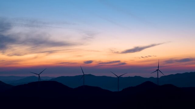 Four Wind Turbines Silhouetted Against Twilight Sky Over Layered Mountain Ridges, Real Time Footage of Renewable Energy at Dusk
