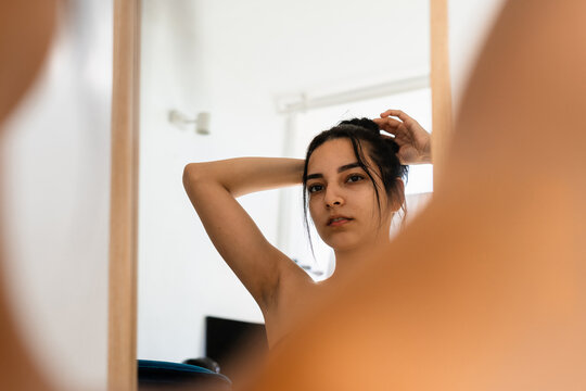 A woman fixing her hair in front of the mirror at home