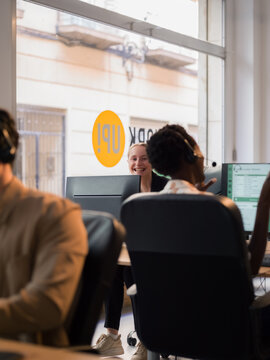 Employees are talking and smiling while working at call center 