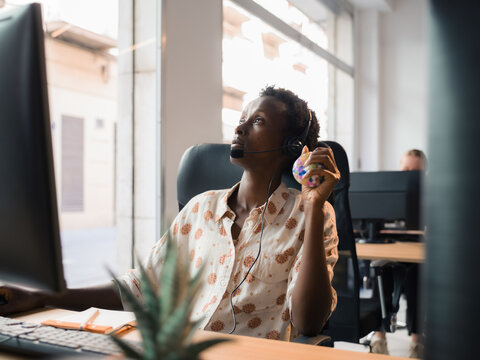 Call center worker squeezing stress ball during call with client 