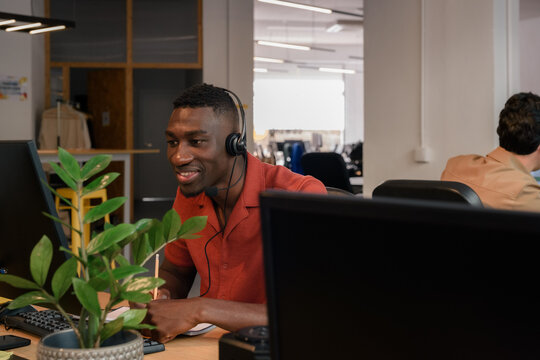 Man wearing headset is looking at screen and talking to client 