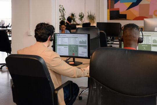 Workers Sit in an Office Using Computers and Headsets for Calls