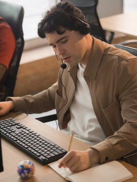 Help desk worker writing notes during call with client 