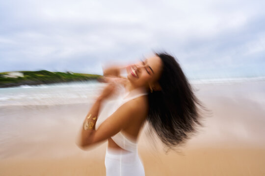 Woman experiencing joy and freedom on beach, motion blur
