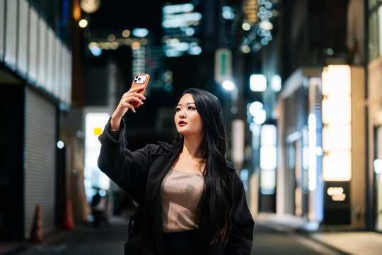Woman taking a selfie in Tokyo city at night