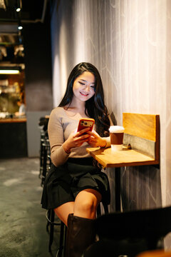 Japanese woman smiling using smartphone in Tokyo cafe at night