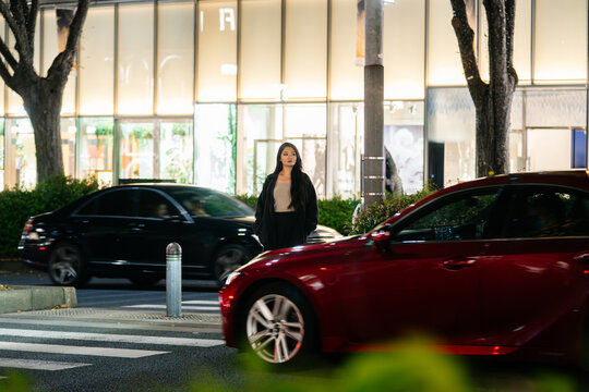 Japanese woman crossing urban Tokyo street at night