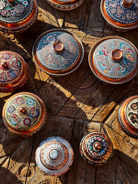 Close-up of colorful painted copper bowls on a carved wooden sur