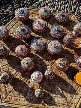 Ornate hand-painted copper bowls arranged on a carved wooden tra