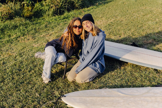 UGC Two friends sitting with surfboards on grass during autumn surf tr