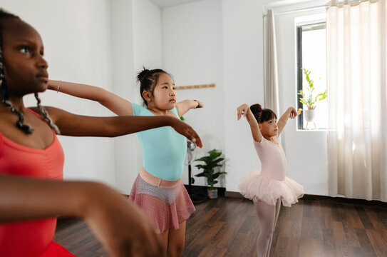 Diverse young girls learning ballet positions in studio