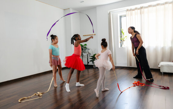 Instructor guiding young girls learning rhythmic gymnastics