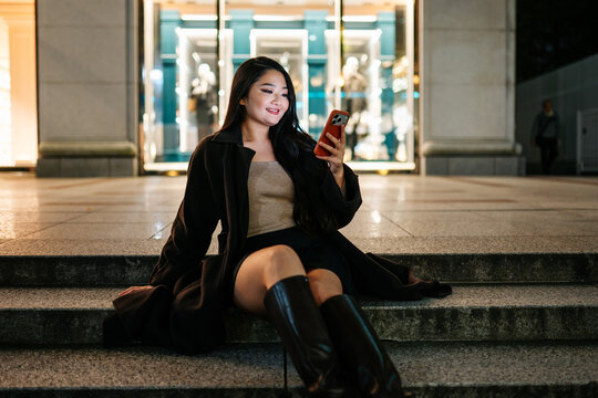 Japanese woman using smartphone on Tokyo city steps at night
