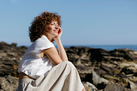 Woman smiling on sunny beach rocks