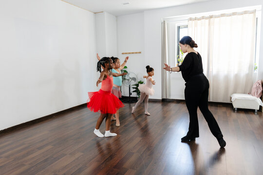 Girls learning ballet movements from dance teacher