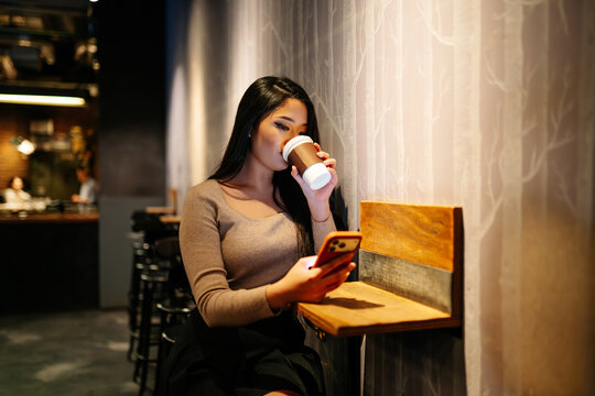 Japanese woman enjoying coffee and smartphone in Tokyo cafe