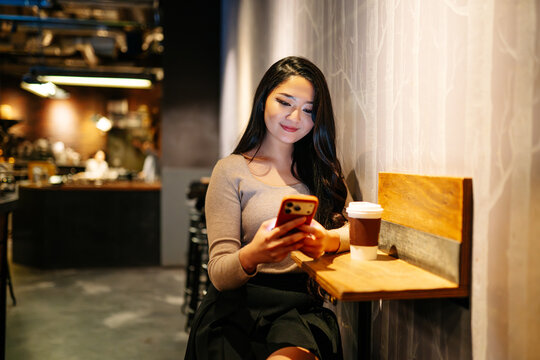 Japanese woman using smartphone in Tokyo cafe at night