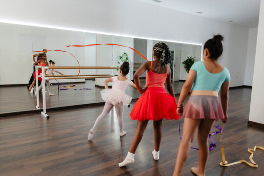 Diverse girls practicing dance in studio with instructor