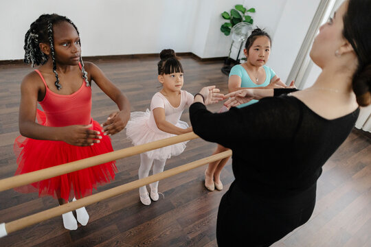 Children learning ballet positions receiving instruction from teacher