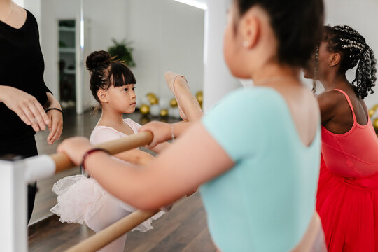 Young ballerinas practicing ballet steps at studio barre
